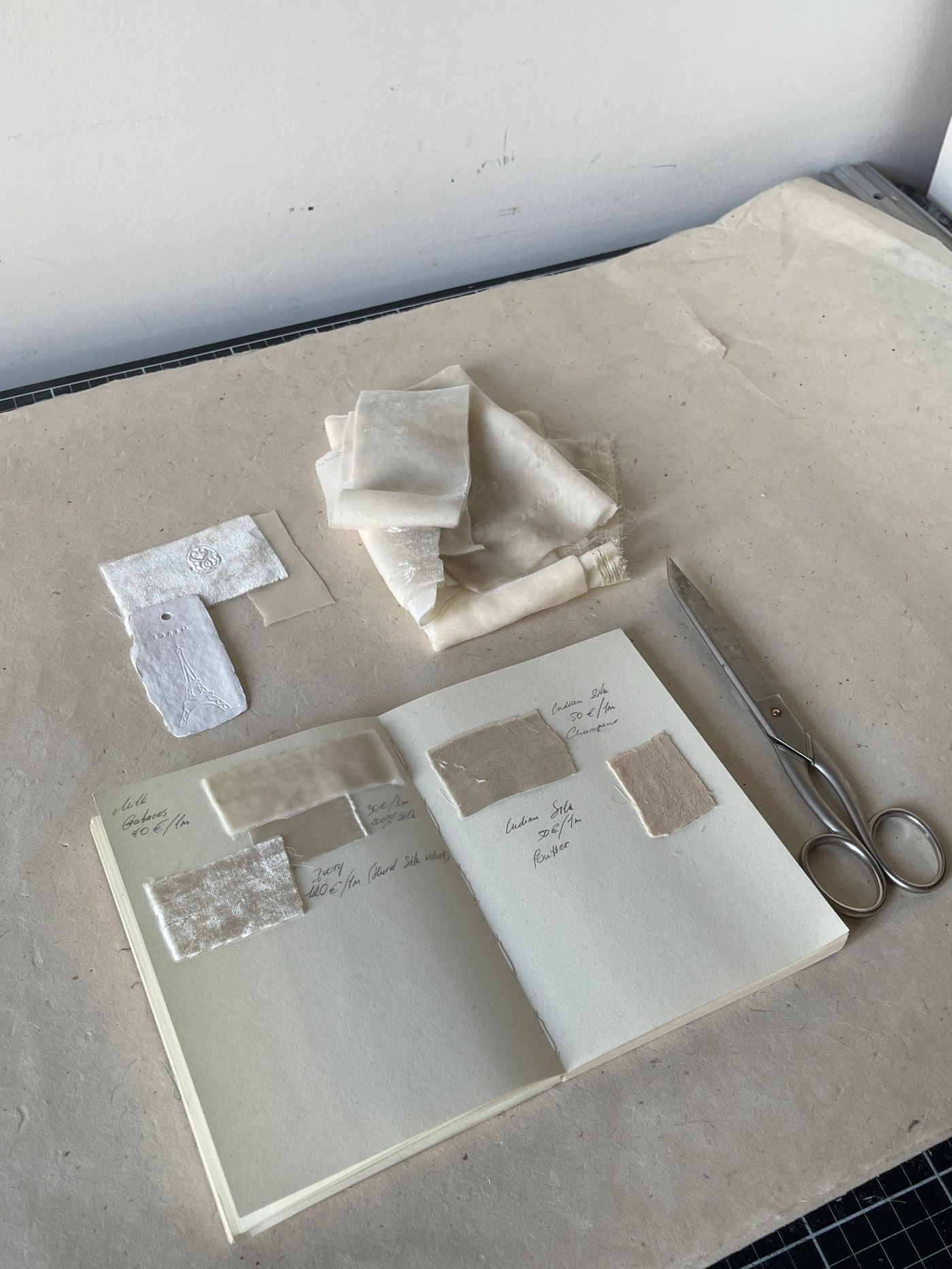Fabric swatches in an open notebook beside scissors